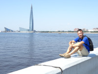 2021.07.11 Sitting on a border curb of the Neva Bay embankment against the background of the Lakhta Center.