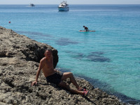 2021.07.28 While I am sitting-reclining on the rocks of the picturesque Ayia Napa's beach “Sweet Water” (Γλυκυ νερο), a woman far away is trying to get up on a SUP. 😁